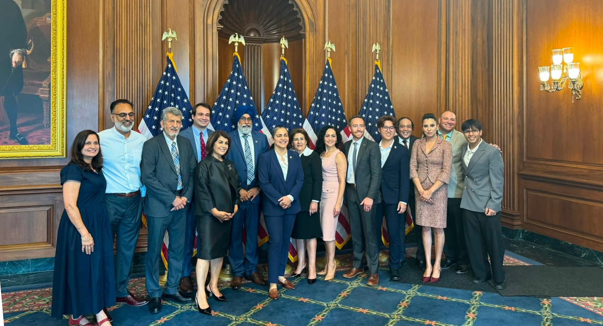 A group poses in a wood-paneled room in front of American flags