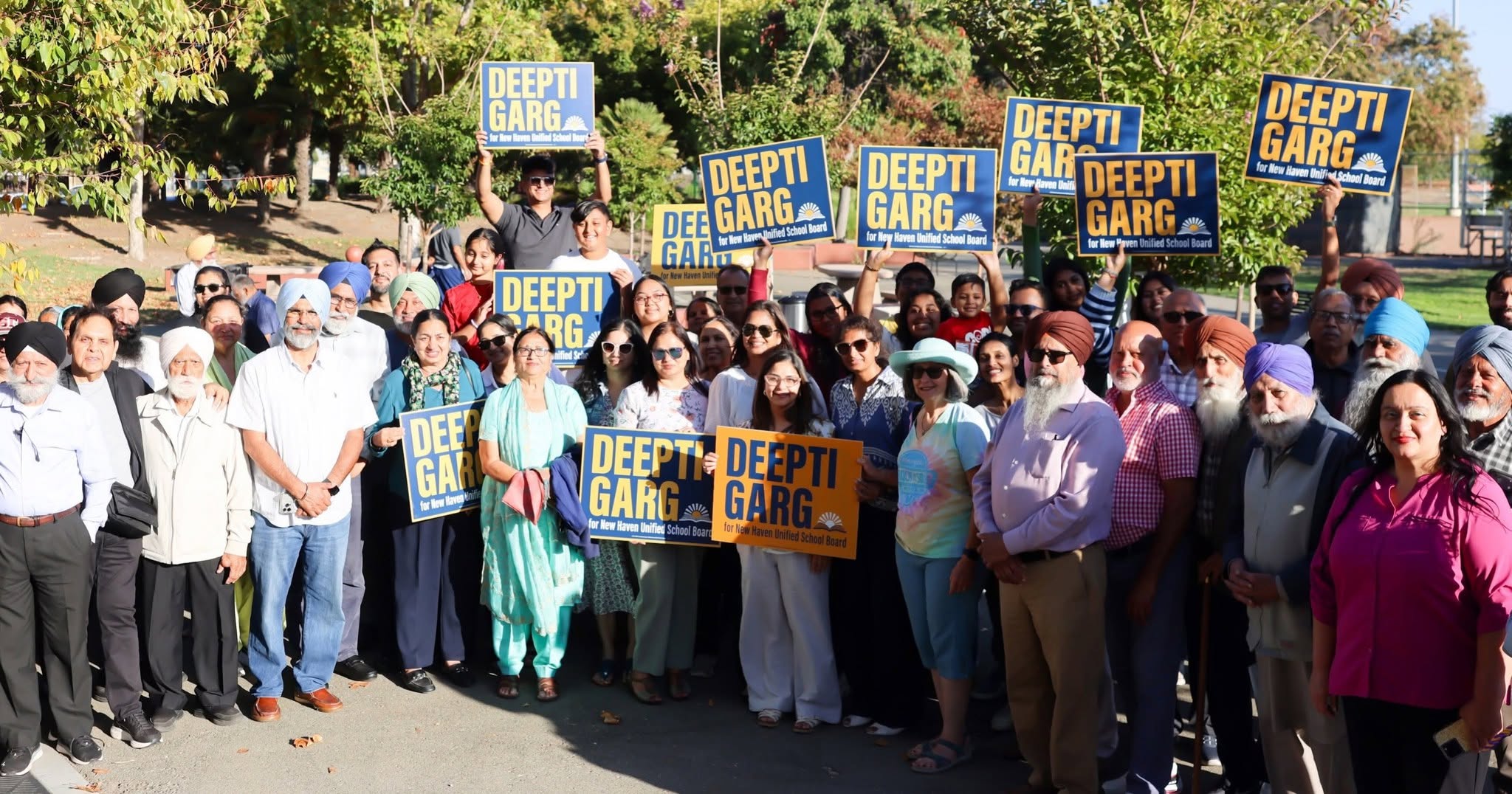 A group poses outdoors, with several people holding Deepti Garg for New Haven Unified School Board signs